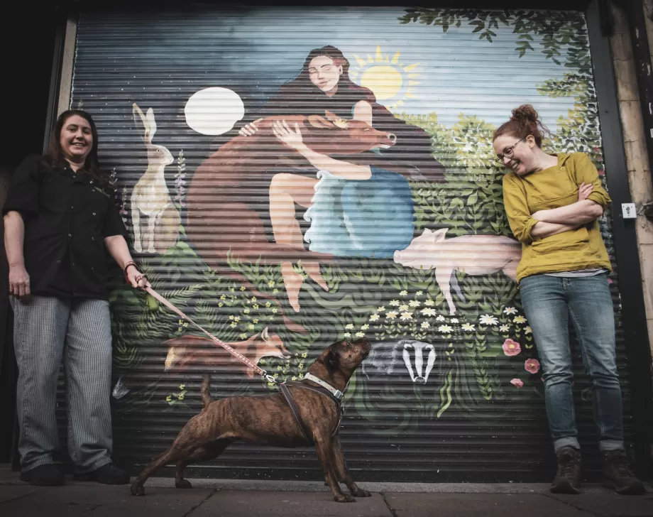 Katie and Catherine with their dog in front of their restaurant