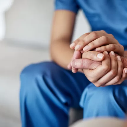 Person in scrubs holding someone's hand reassuringly