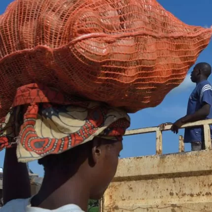 Woman carrying bag of onions on head