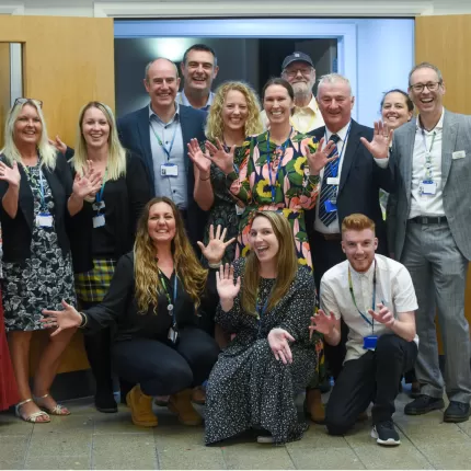 Coastline Housing team standing in a group waving