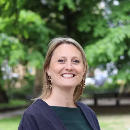 Katherine Chapman, the blog's author, facing the camera and smiling against a blurred background of trees in a park.