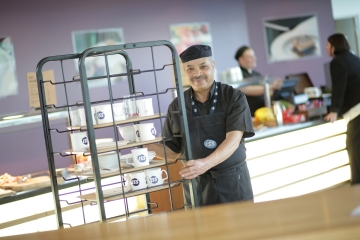 Man working in canteen pushing trolley